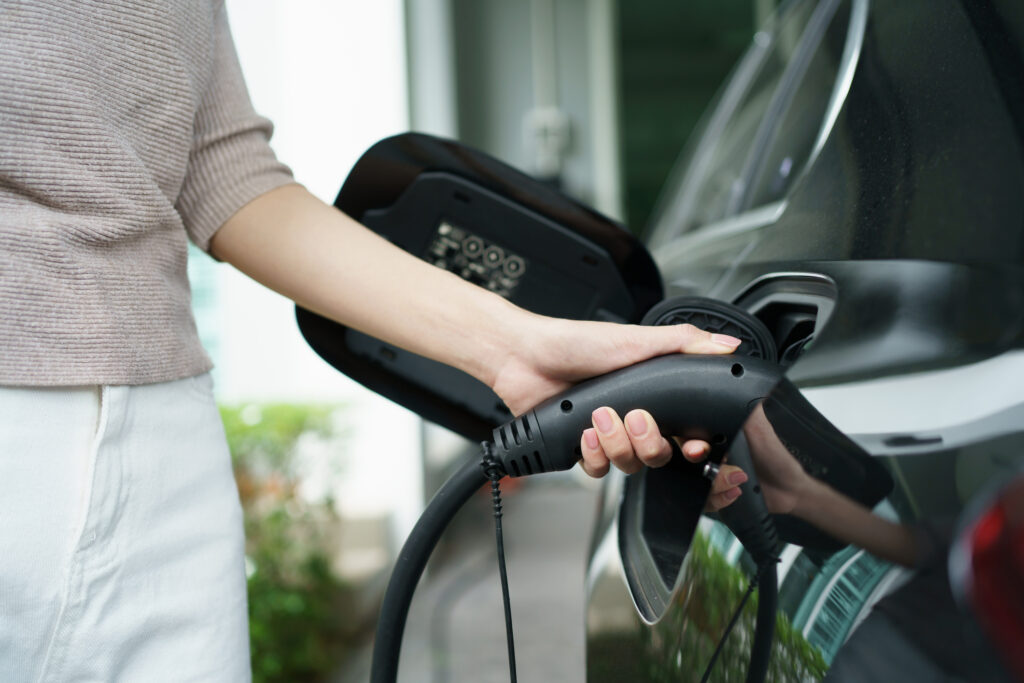 A woman charges her black electric vehicle for does-EV-charger-brand-matter blog.