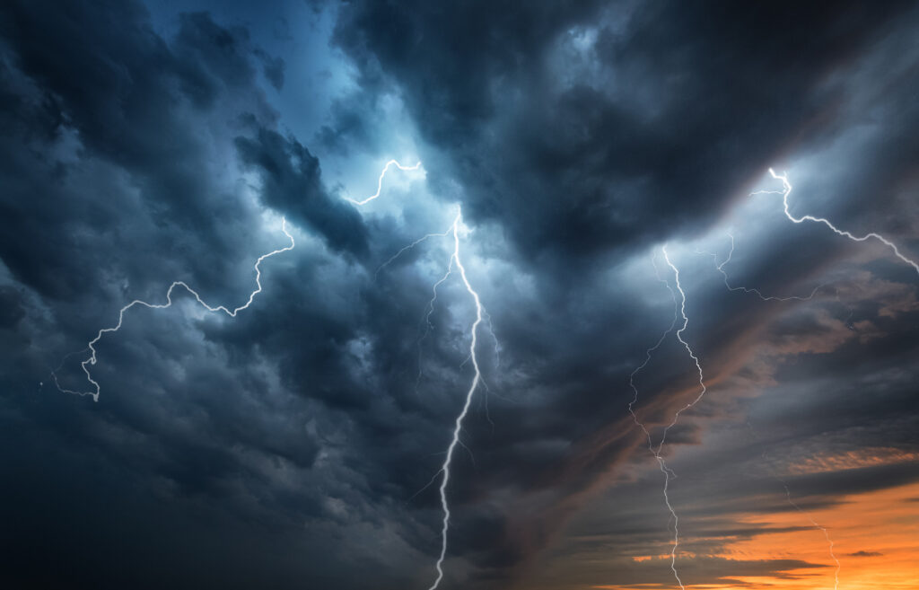A lightning storm flashes in a night sky for should-i-unplug-my-ev-charger-during-a-thunderstorm blog.